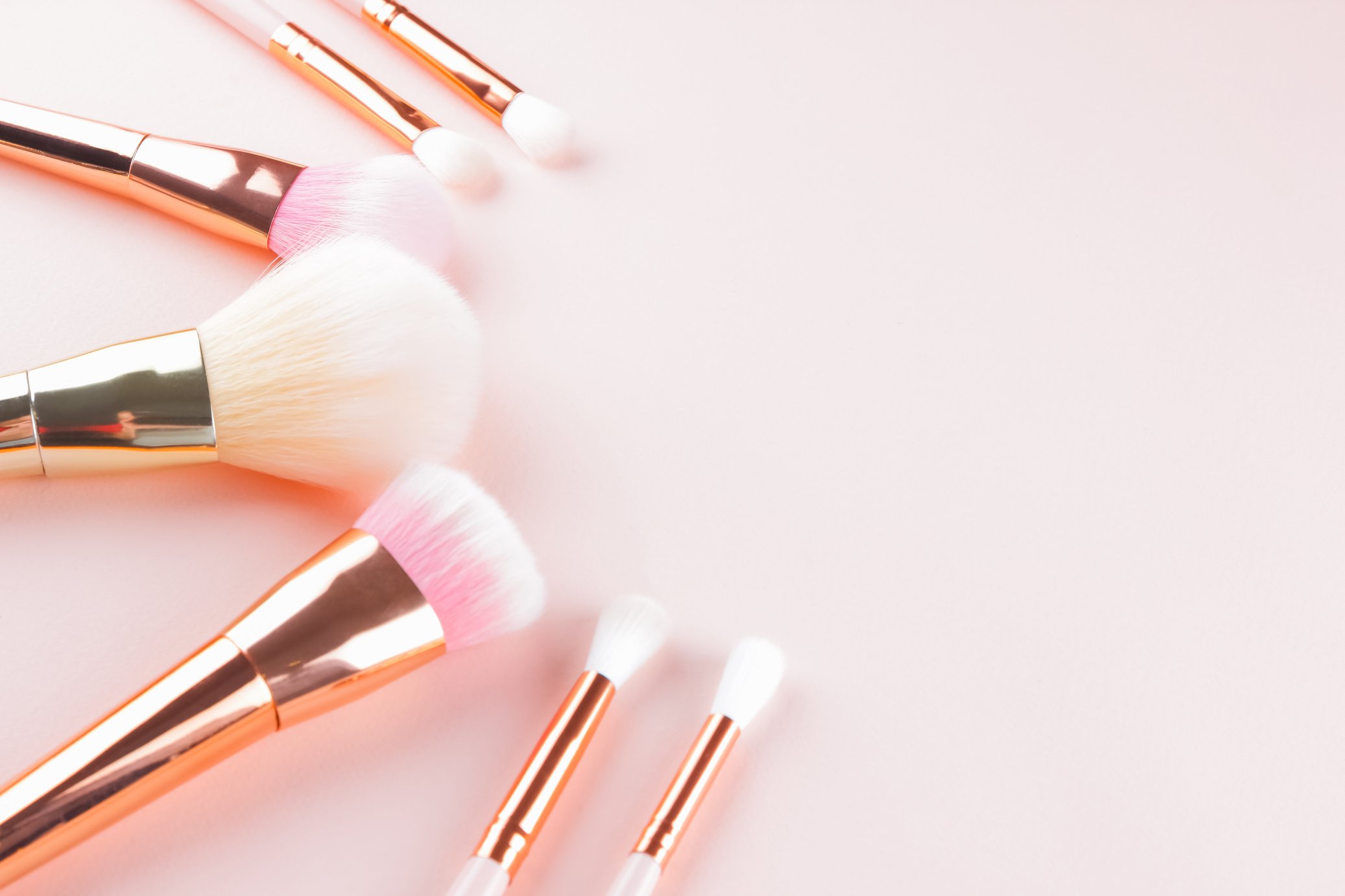 Makeup brushes on pink background. Set of golden makeup brushes,